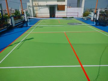 Empty rooftop badminton court with green flooring.