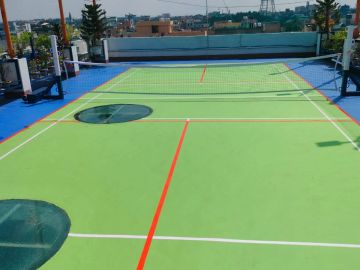 Rooftop tennis court with colorful markings.