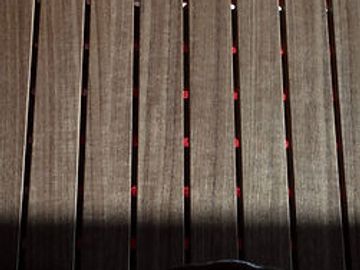 Close-up of wooden slats with small red dots between them.