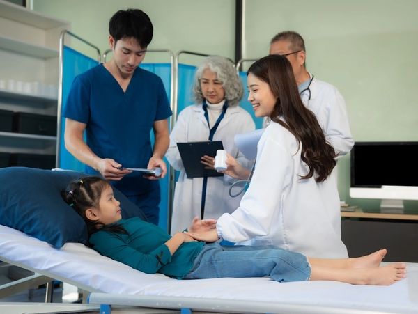 Doctors examining a young girl lying on a hospital bed, providing care and medication.