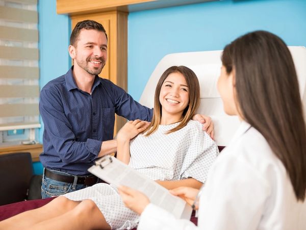 Pregnant woman with partner consulting a doctor in a clinic.