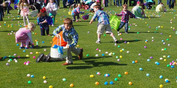 Children enthusiastically collecting colorful Easter eggs in a park.