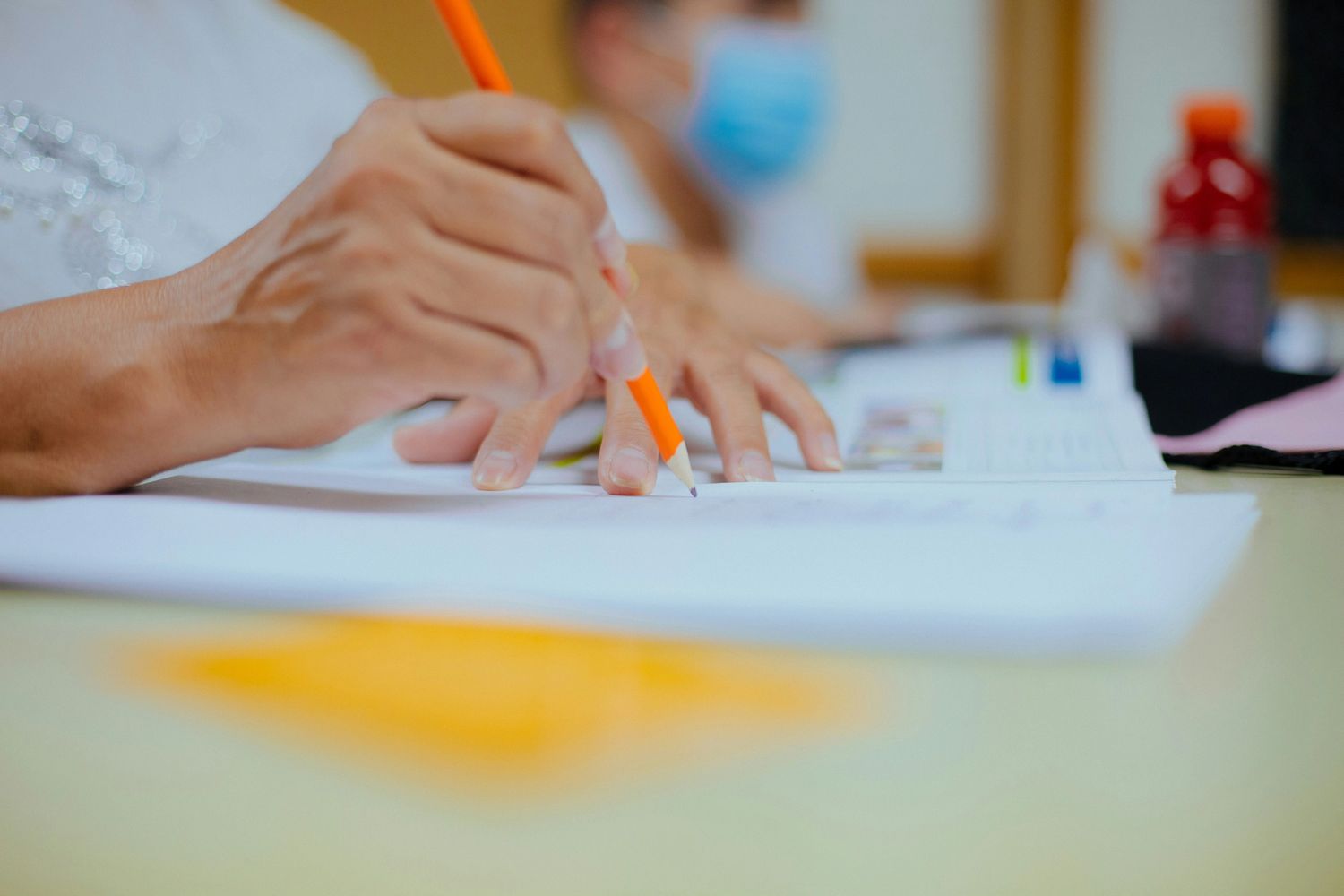 Close-up of a person writing with a pencil on paper.