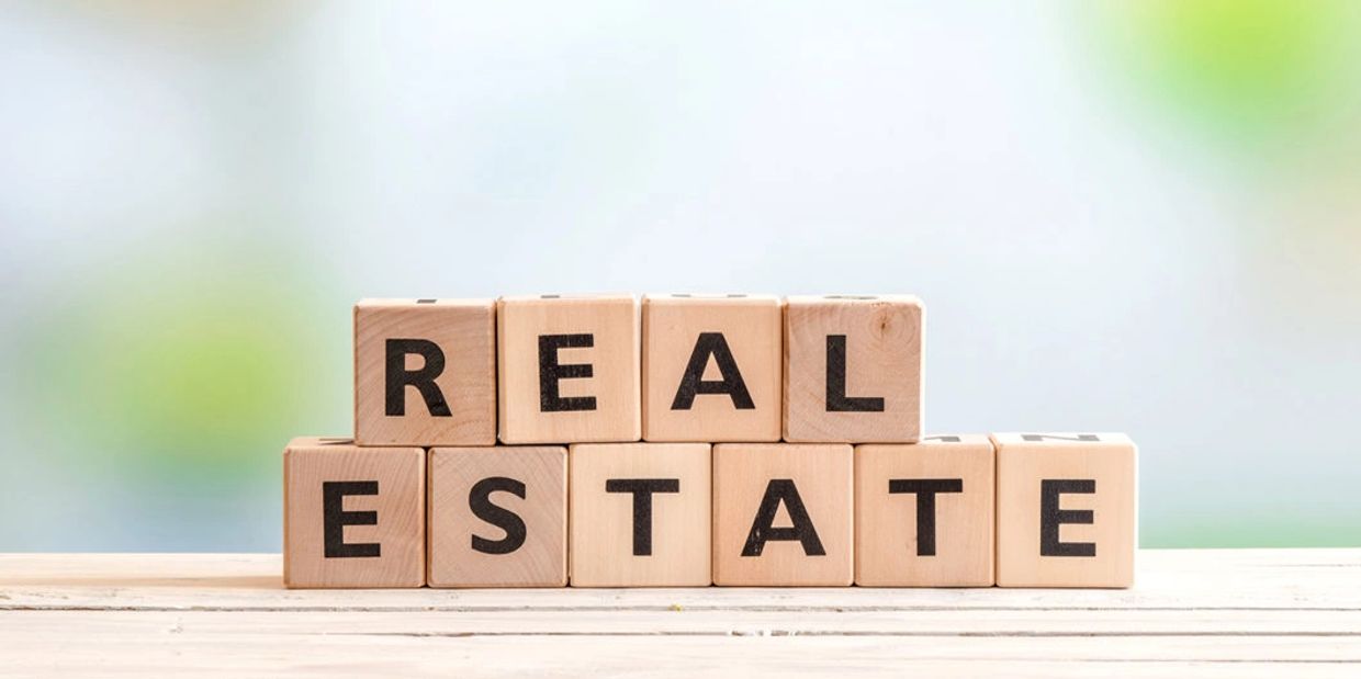 Wooden blocks spelling "REAL ESTATE" on a table.