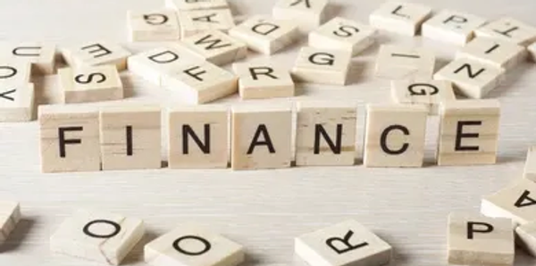 Scrabble tiles spelling 'FINANCE' on a wooden surface.