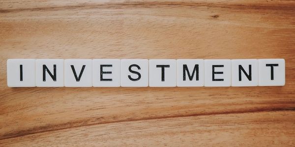 Scrabble tiles spelling out 'INVESTMENT'.