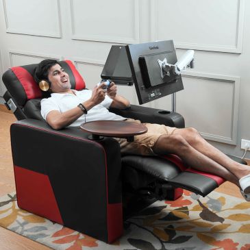 Man playing video games comfortably in a recliner with a mounted monitor.