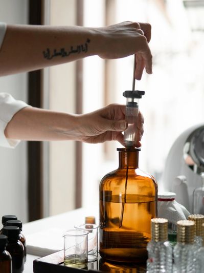 Person using a dropper to extract liquid from an amber glass bottle.