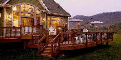Custom elevated wood deck with railing, lighting, and mountain views at sunset