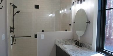 Renovated bathroom with glass walk-in shower, granite vanity, and updated lighting 