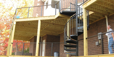 Multi-level deck with black metal spiral staircase and cable railing by Full Circle Building Group