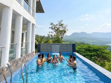 Group of friends enjoying a pool with a scenic mountain view.