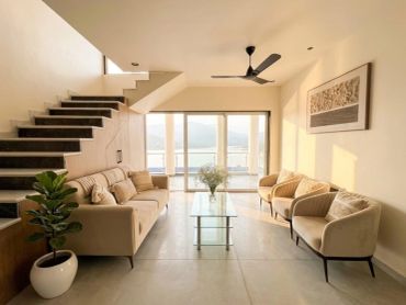 Modern living room with beige furniture and large windows.