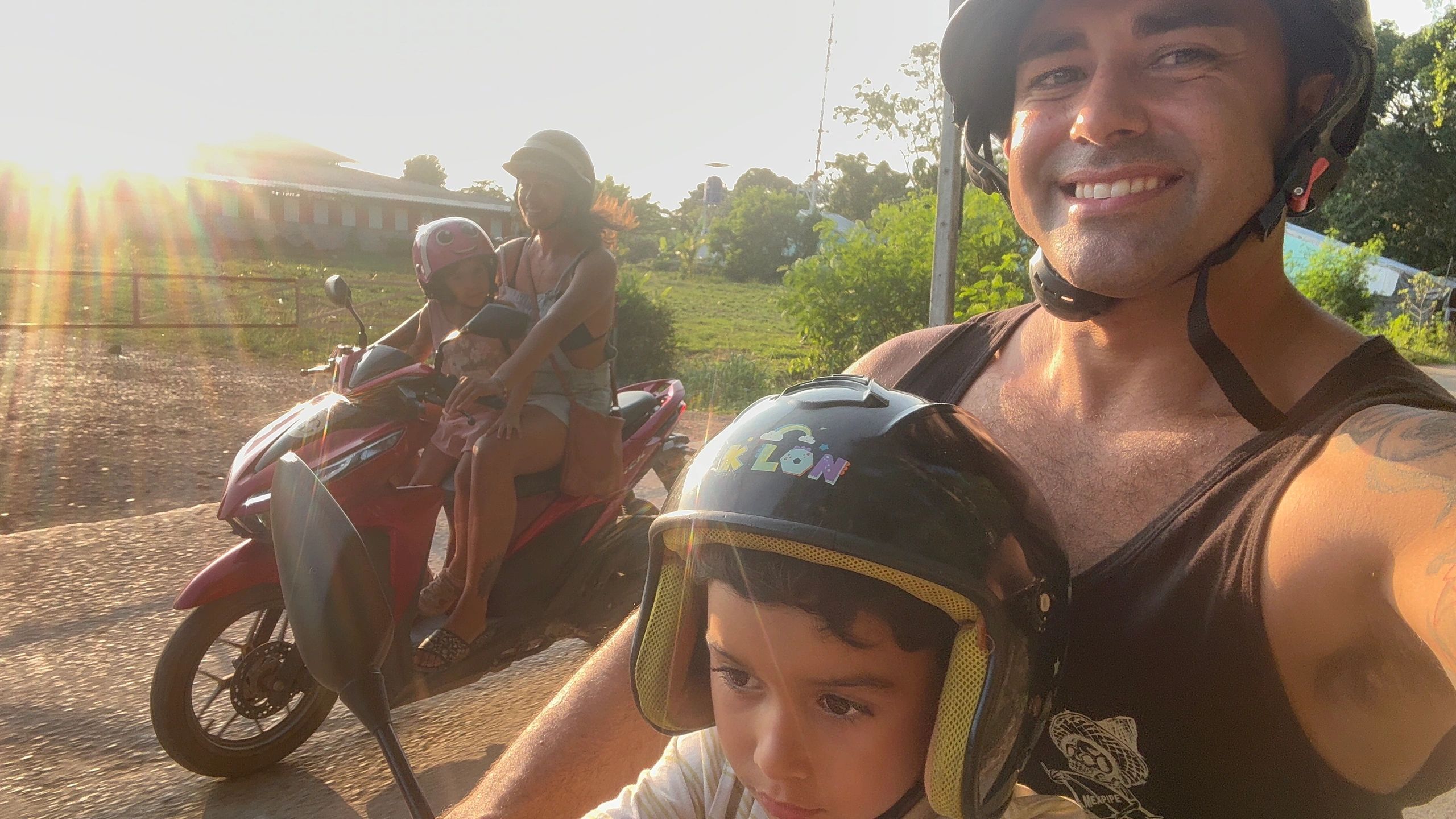 Family of four riding motorcycles together at sunset, all wearing helmets.