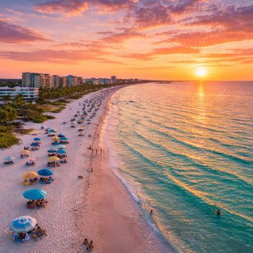 Sunset over a lively beach with colorful umbrellas and buildings.