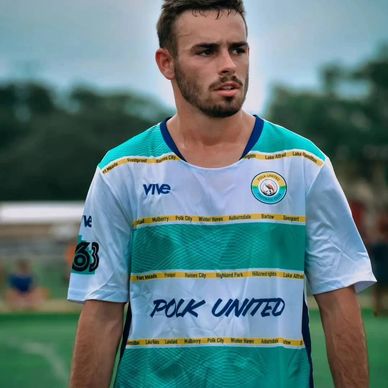 Male soccer player wearing a Polk United jersey on the field.