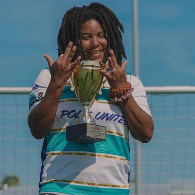 Athlete proudly holding a trophy on a soccer field with a bright smile.