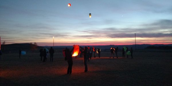 Teams of friends releasing lanterns at sunset.