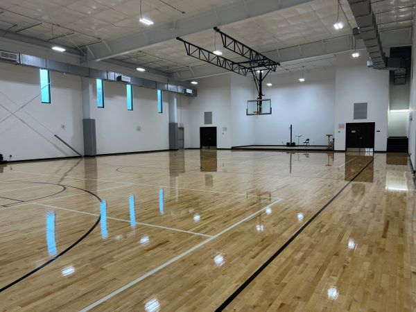 A clean, empty indoor basketball court with polished wooden floors.