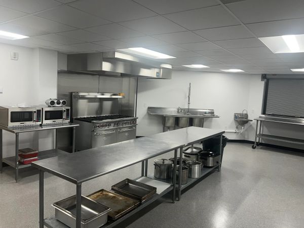 Clean commercial kitchen with stainless steel appliances and worktables.