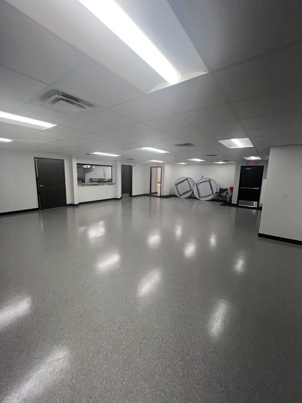 Empty, well-lit room with gray floor and white walls.