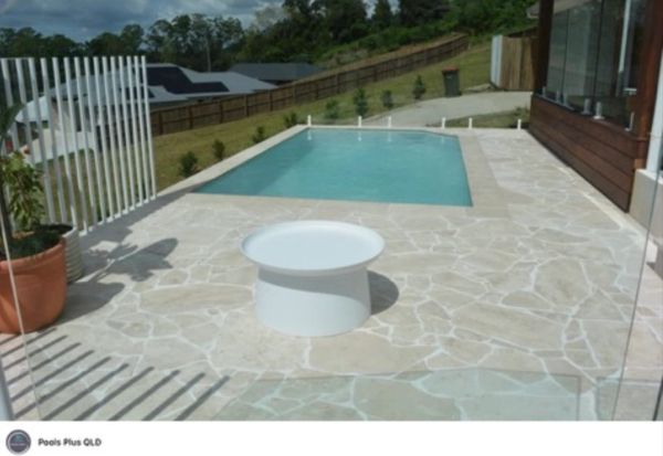 Rectangular backyard pool with surrounding patio and central white table.
