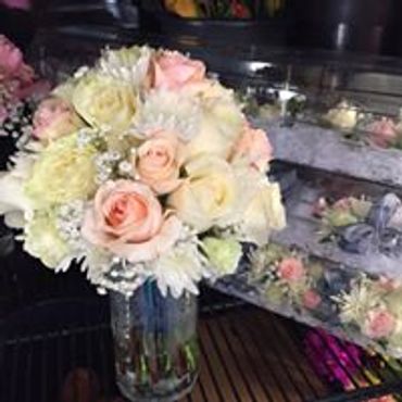 A bunch of pastel-colored flowers in a tall glass vase