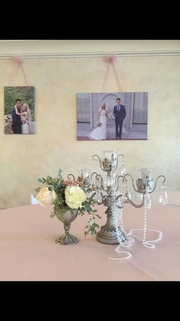 A silver vase with white roses and greenery on pink table