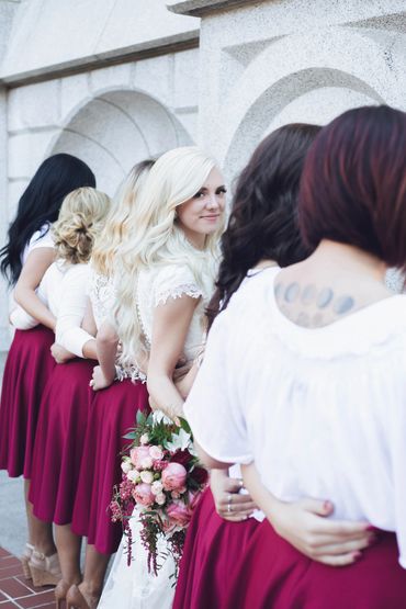 A row of bridesmaids with white tops and red skirts