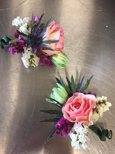 A pink boutonniere with small white flowers