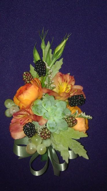 An orange rose corsage with berries and succulent