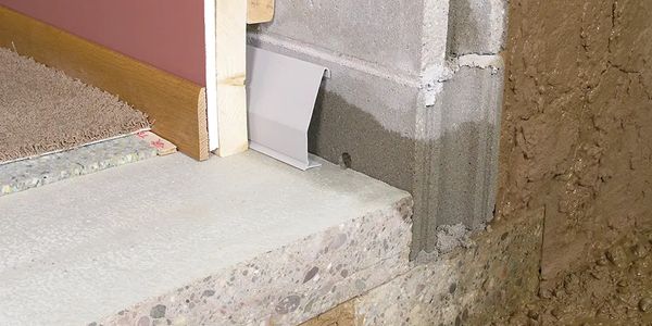 Close-up of a doorway threshold with concrete and unfinished wall surfaces.