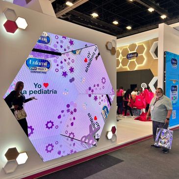 Large hexagonal digital display at a trade show booth promoting pediatric care.