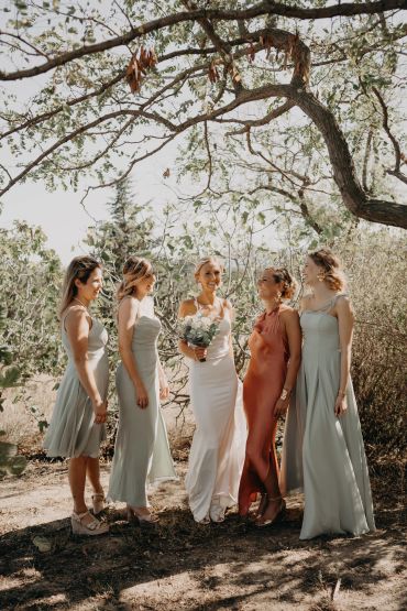 Mariée entourée de demoiselles d'honneur en robes élégantes à l'extérieur.