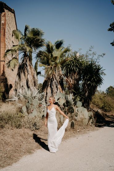 Femme en robe blanche marchant près de cactus.