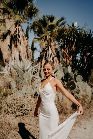 Femme en robe blanche sous le soleil près des cactus.