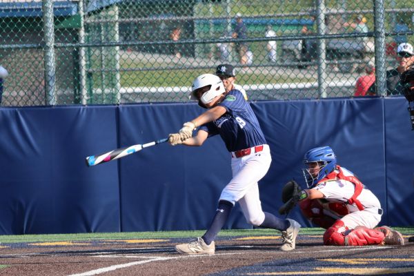 Young baseball player hitting the ball during a game.