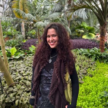 Smiling woman standing in a lush garden.