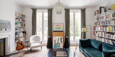 Bright living room with bookshelves, a green sofa, and large windows.