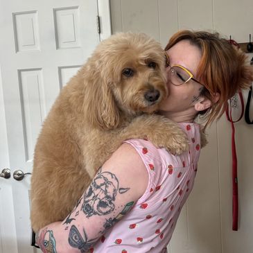 Person hugging a fluffy dog indoors.