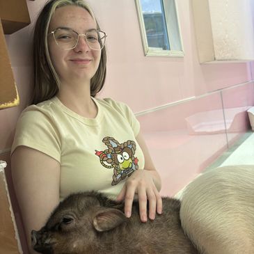 Woman smiling with a pig resting on her lap.