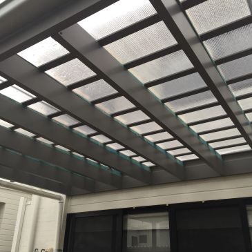 Modern patio roof with transparent panels and metal beams.