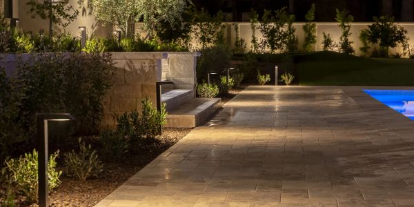 Outdoor pathway lighting at night near a pool and garden.
