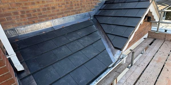 Newly installed black roof tiles on a residential building section.