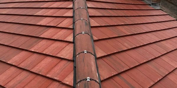 Close-up of a red tiled roof with a ridge covered by a metal cap.