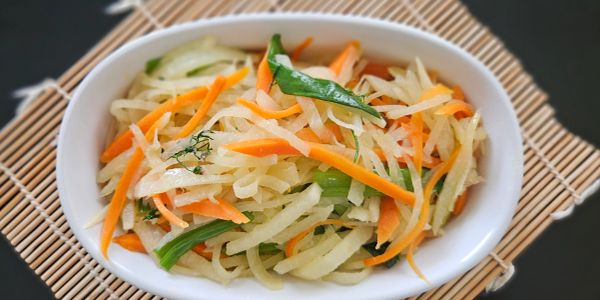 A bowl of mixed vegetable stir-fry with carrots and greens.