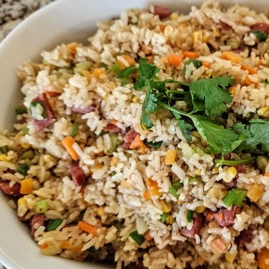 A bowl of colorful fried rice garnished with fresh cilantro.