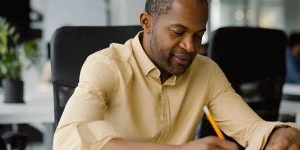 Man writing at desk in office.