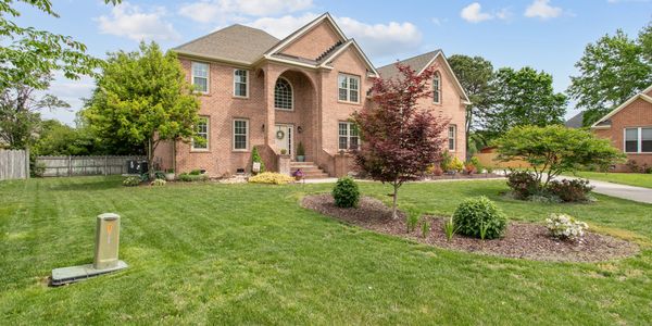 A large brick house with a well-maintained lawn and landscaped garden.