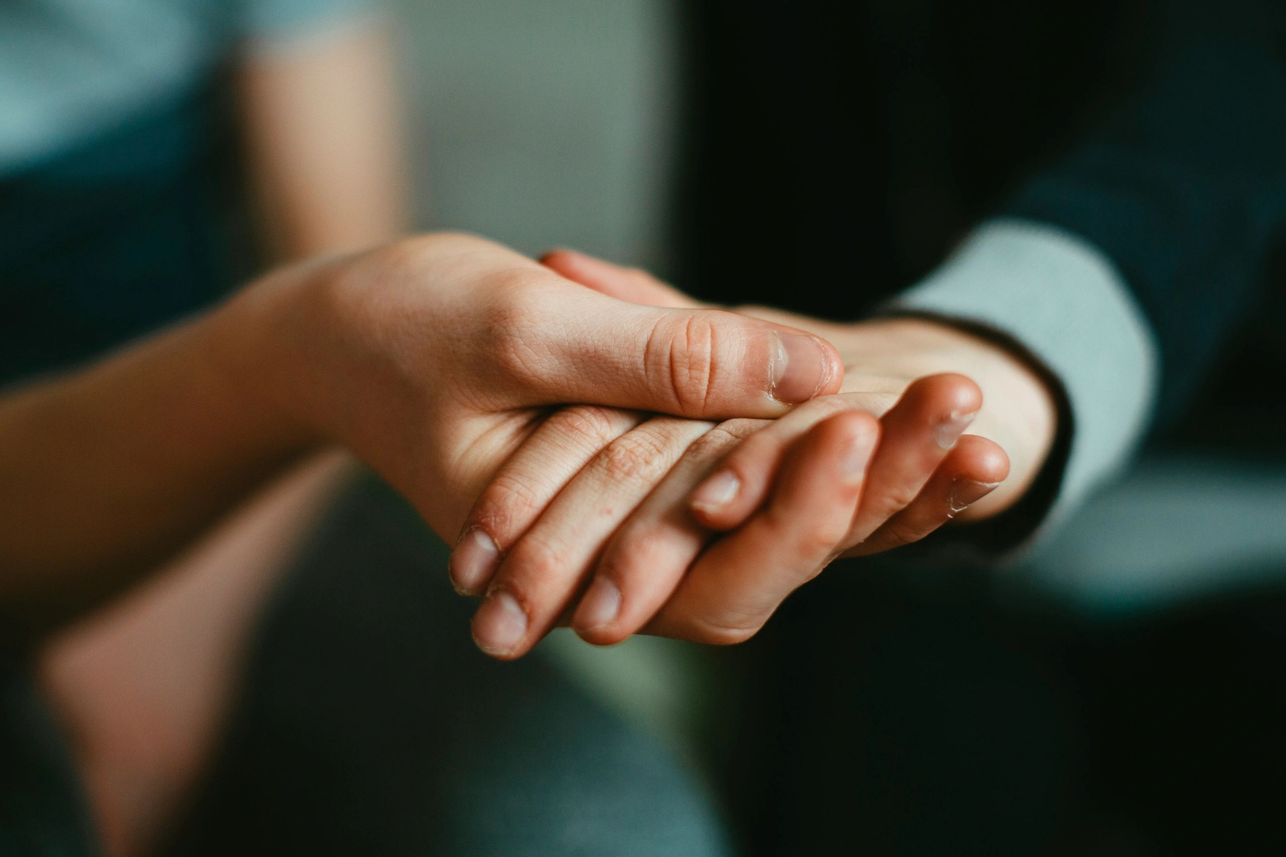 Close-up of hands gently holding each other.